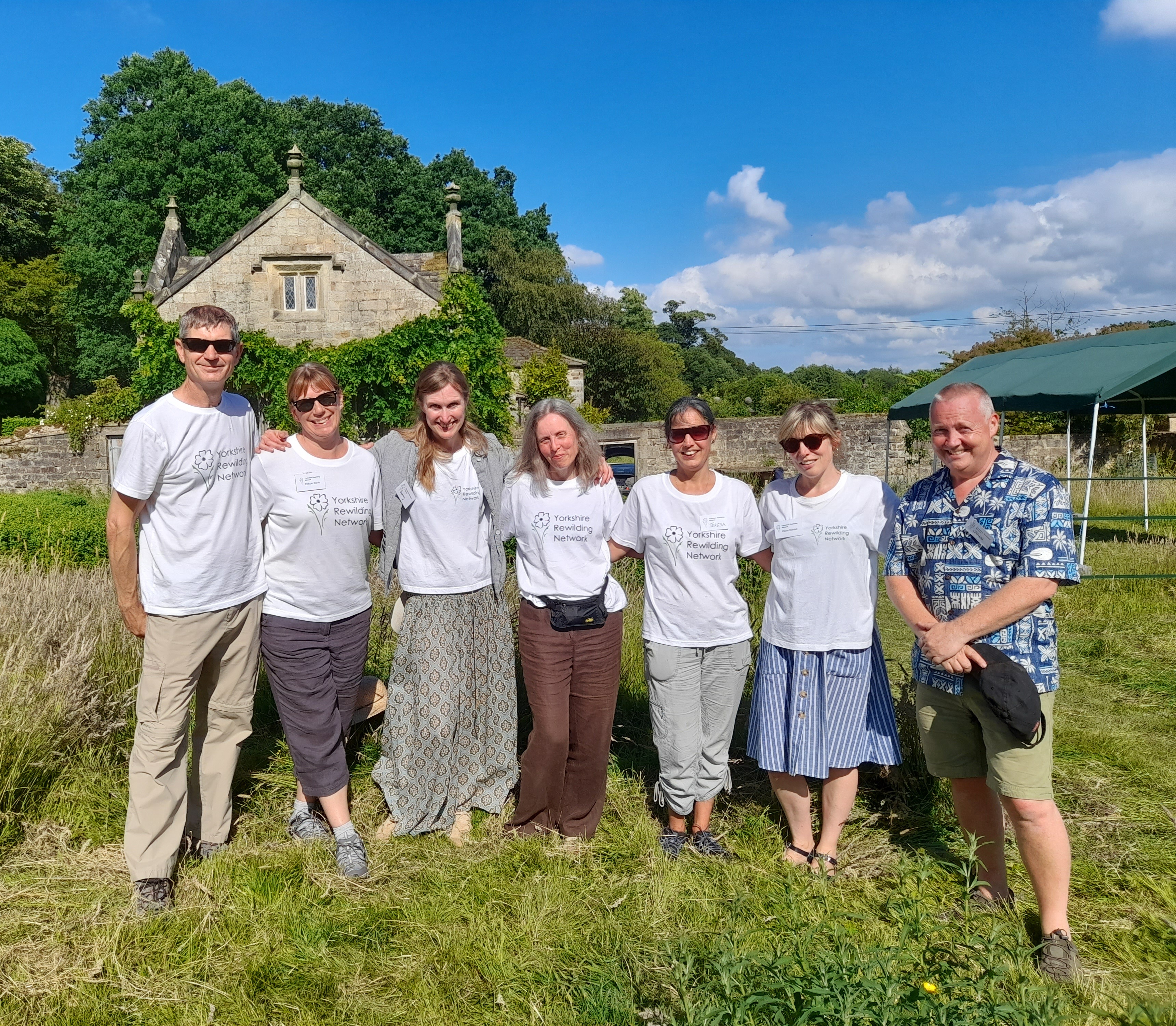 Members of the Yorkshire Rewilding Network posing for a photo in a field on a sunny day.