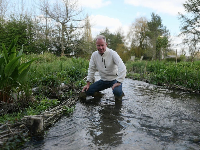 Springwise employee crouching down in a shallow steam doing some surveying