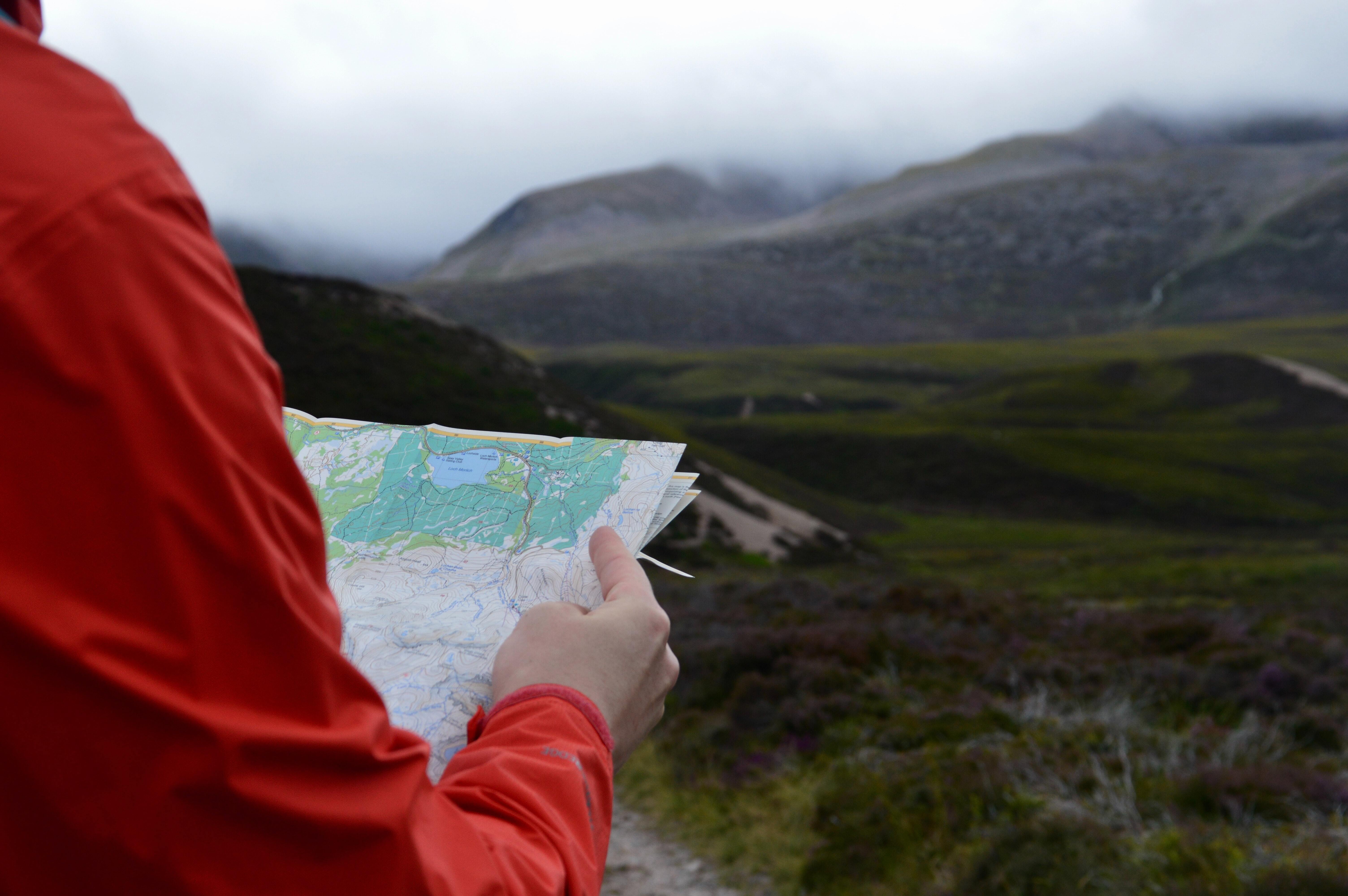 Person holding a map looking out onto a landscape.
