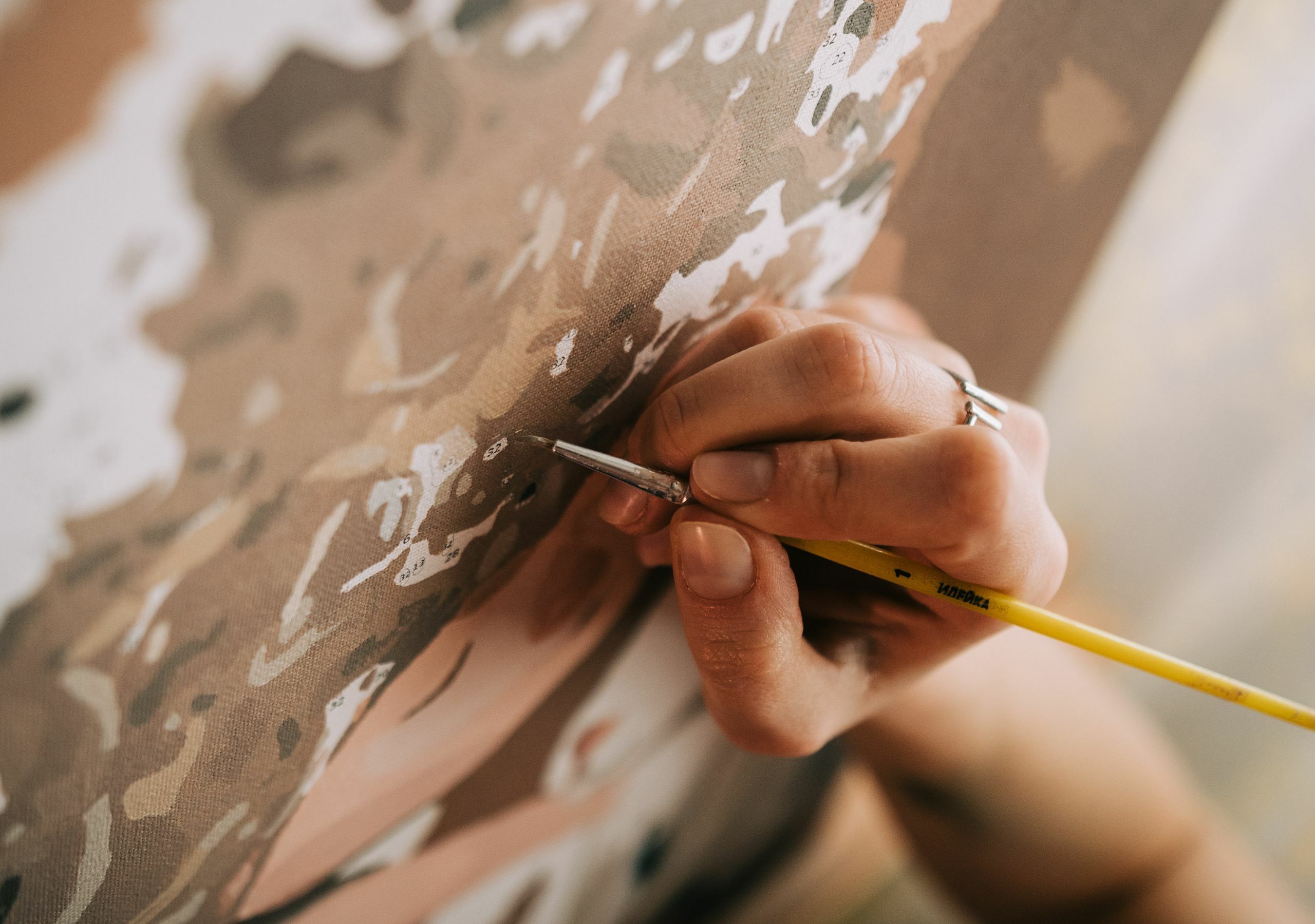 An artist's hand painting on a canvas