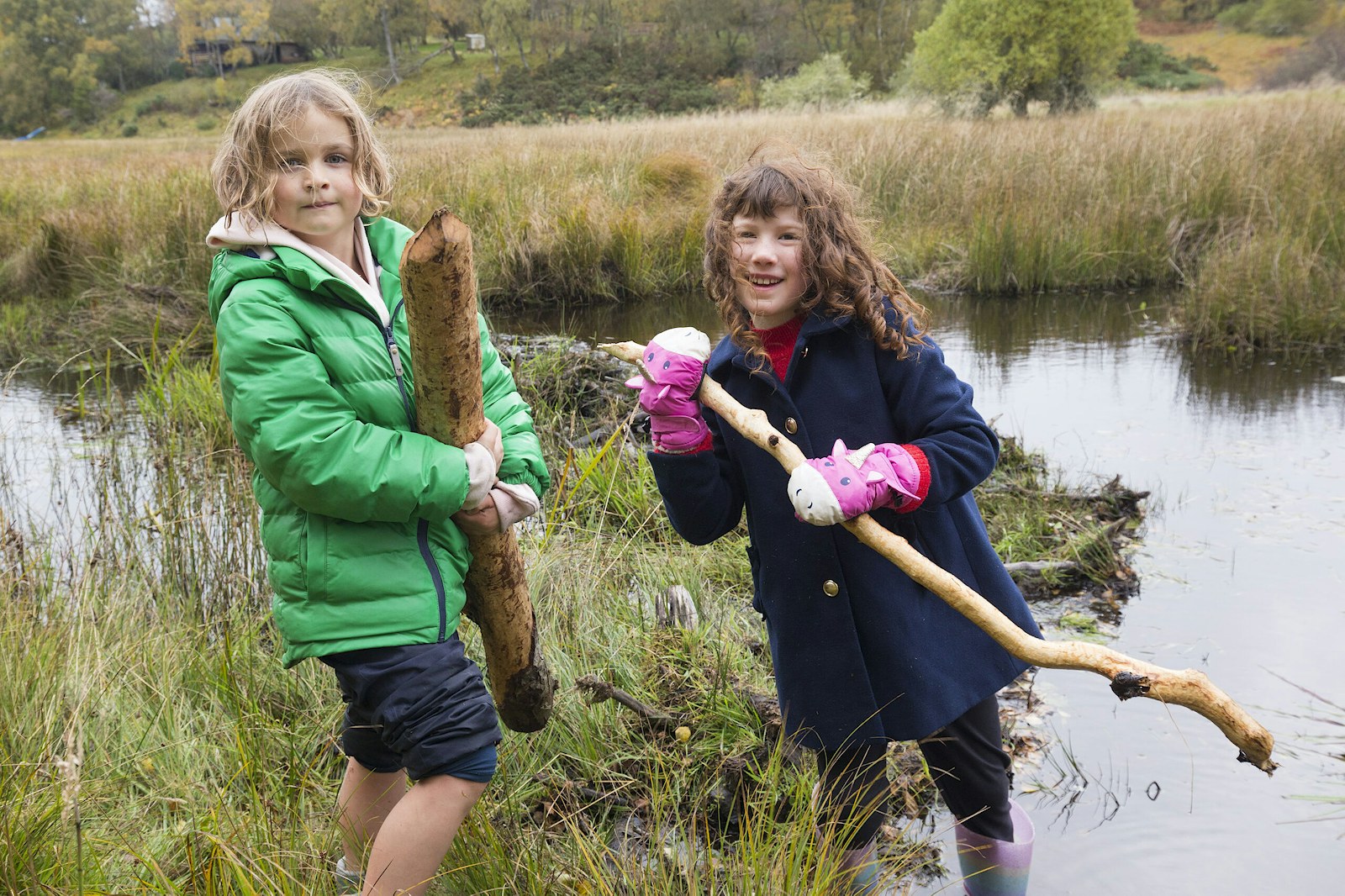 Two children holding beaver gnawed sticks at a gathering of the local community for a ‘beaver day’, organised by Northwoods partner, The Abriachan Forest Trust. Hosted by South Clunes Farm, near Inverness.