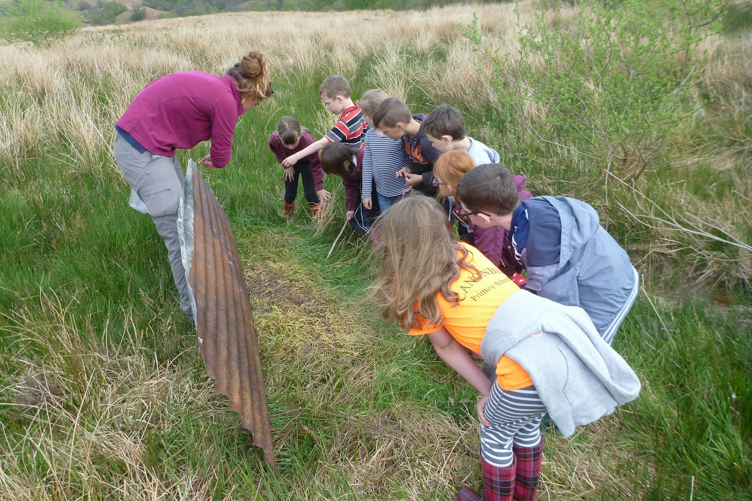 Children crouch to listen to speaker at Tarras Valley, Langholm