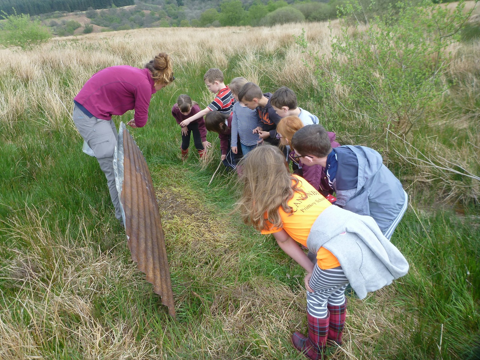 Children crouch to listen to speaker at Tarras Valley, Langholm