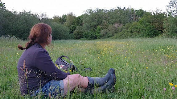 A woman collecting data in a field at Knepp Wildland