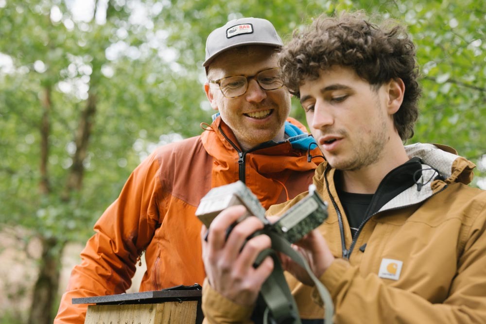 Two men monitoring with camera trap at rewilding site Tir Natur