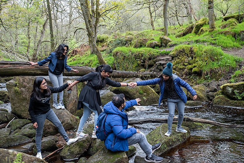 Family of five holding hands and enjoying the Stepping Stones in Peak District