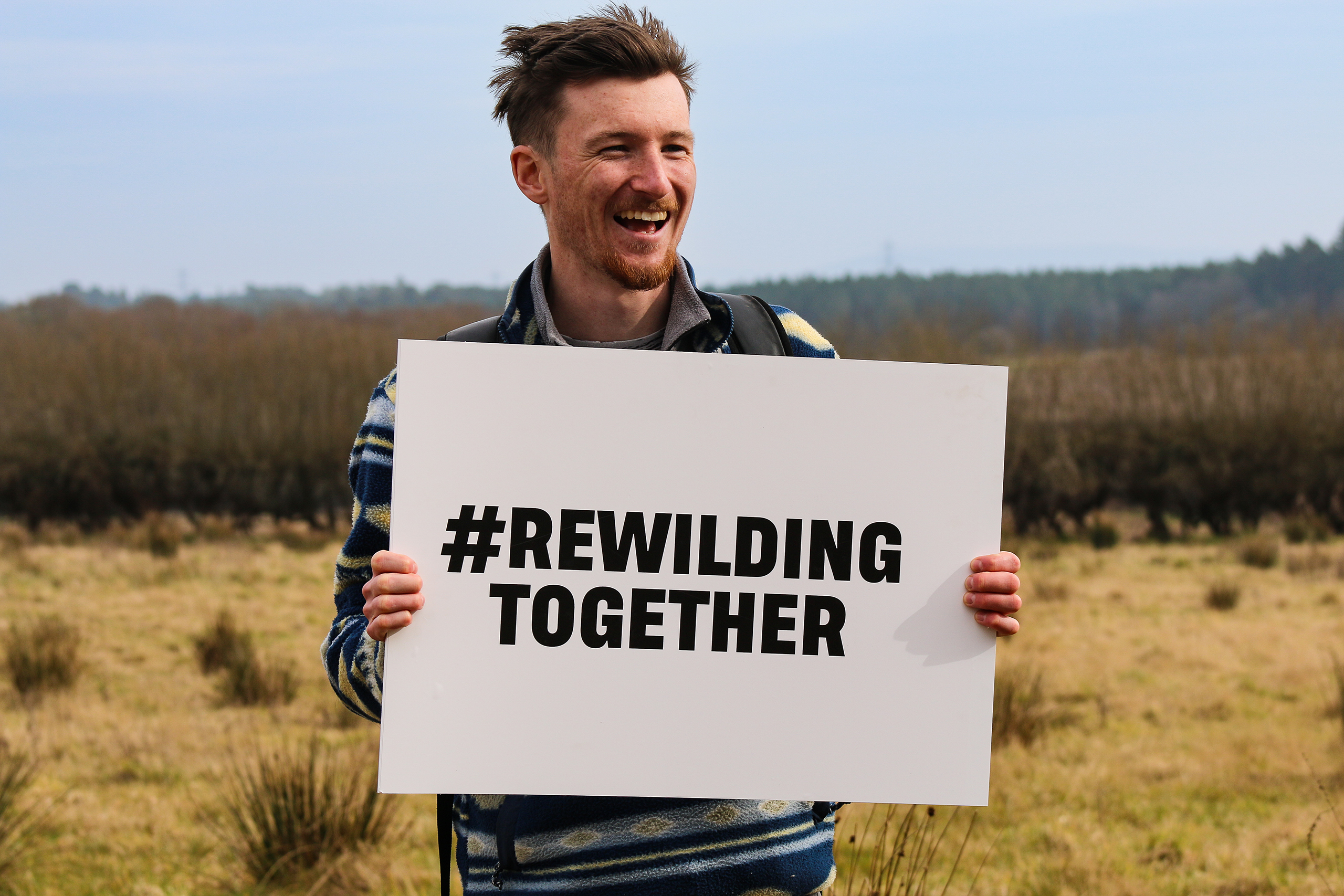 Man holding rewilding together sign