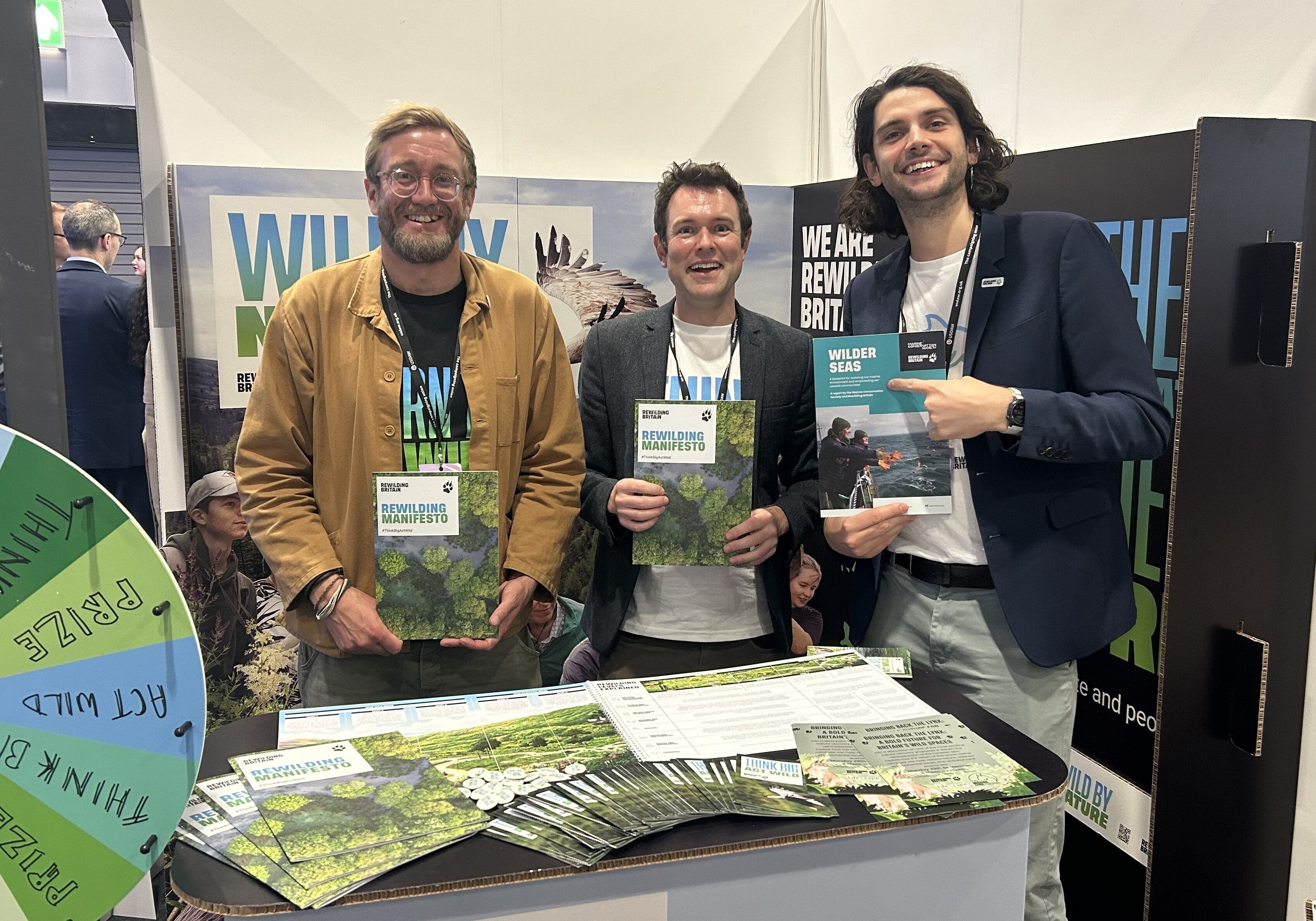Rewilding Britain employees James Hitchcock, Oliver Newham and Jacques Villemot stood at Rewilding Britain's stand at a political party conference.
