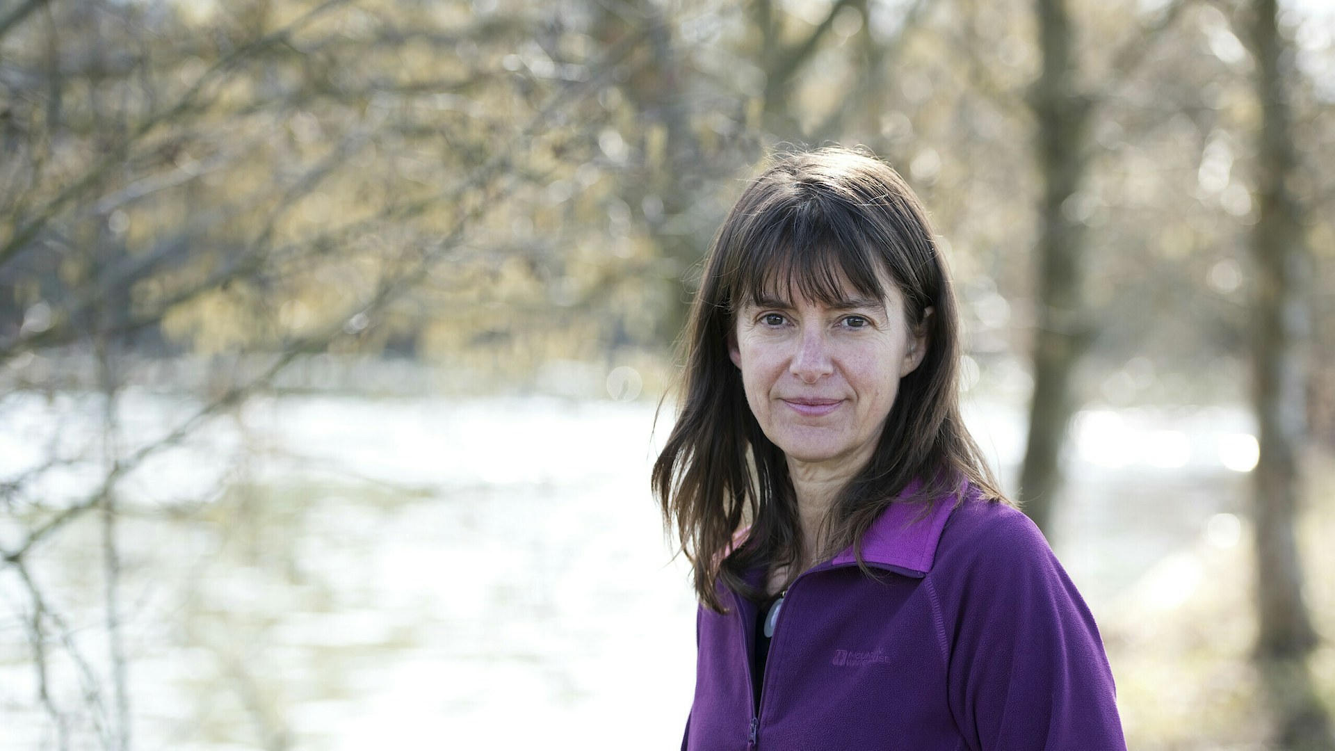 Rebecca Wrigley standing by a lake surrounded by trees