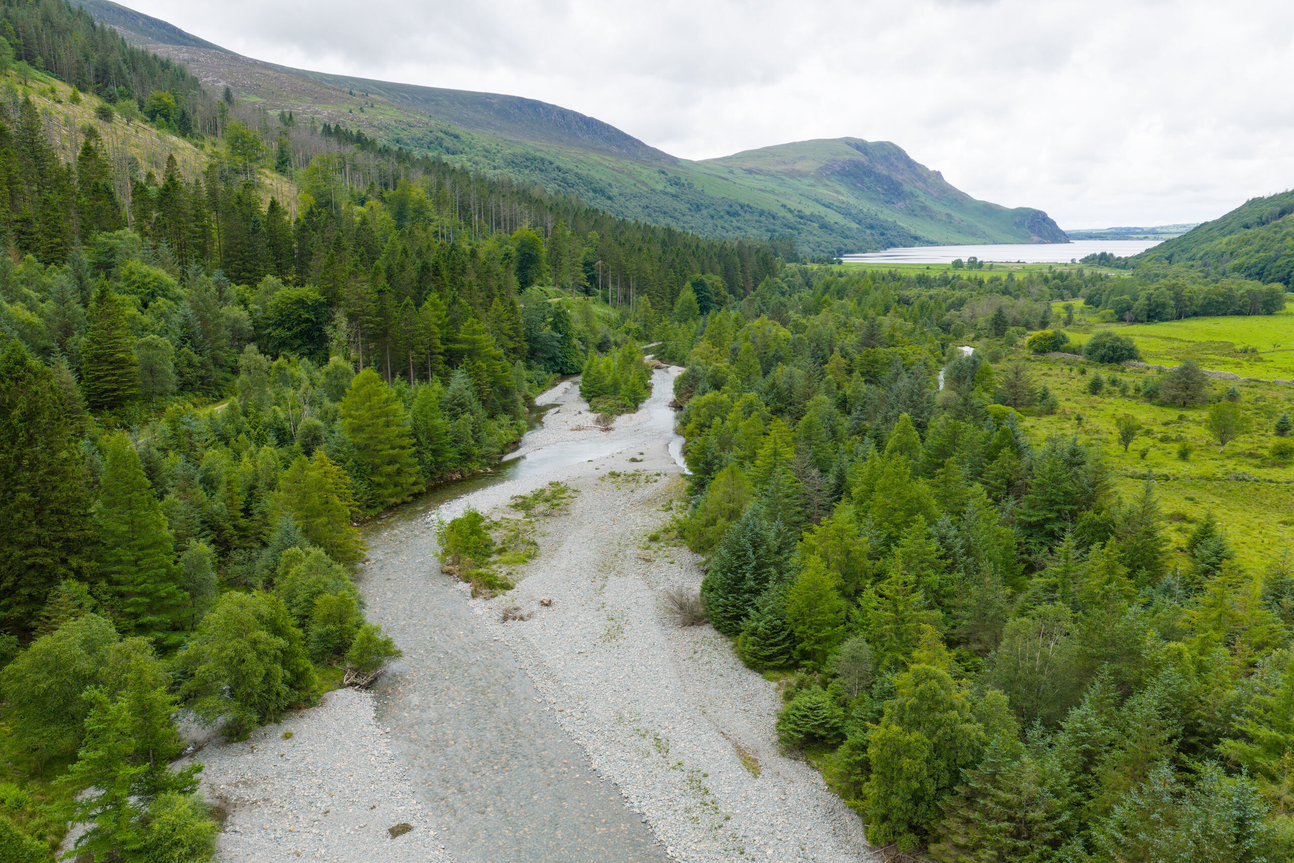 Aerial photo of a river bed surrounded by trees and hills.